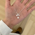 Silver bow necklace featuring a white faux pearl pendant held in hand for size context - Bowknot Pendant with Artificial Pearl Necklace (XL3254)