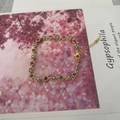 Bracciale dorato con cristallo a cuore viola e ciondoli malocchio su carta decorativa - Viola