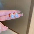 Detailopname van druppelvormige pareloorbellen met iriserende blauwpaarse glans - Zilveren oorknopje-Wit