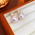 Macro shot of elegant white pearl earrings with gold-plated zircon in a jewelry box - Square Zirconia Gold Pearl Studs