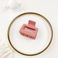 Detailed top view of a matte pink shark hair claw clip on a white decorative plate - Pink