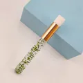 Macro shot of eyelash cleansing brush with green glitter handle and golden metal tube - Glitter Green