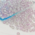 Macro shot of 6mm and 8mm purple cracked glass beads spilling from a glass bowl - 8mm / Light Purple White