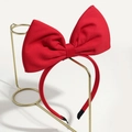 Cute red fabric bow headband for Christmas party, displayed on a gold metal stand - Red Bow