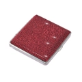 Macro shot of ultra-thin metal cigarette case featuring shimmering red rhinestones on a surface - Red