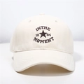 Dettaglio ravvicinato del ricamo a stella e testo su un cappellino beige - Taglia Unica (Regolabile) / Beige