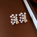 Dettaglio di orecchini vintage a fiori dorati con perle e decorazione a foglia - Oro