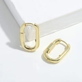 Detail of minimalist gold-plated oval hoop earrings on a white geometric platform - Oval Buckle Style