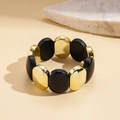 Macro detail of matte black and gold oval bead bracelet on minimalist stone base - Gold/Black