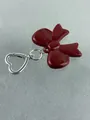 Close-up of red resin bow keychain with silver heart-shaped lobster clasp on grey felt - Burgundy Bow Large Style (Style 6)