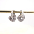 Detail van zilveren hartvormige oorbellen met micro-pave zirkonia op een gouden houder - Zilver