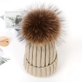 Beige knitted beanie with a large brown faux fur pom-pom on top for winter wear - Camel