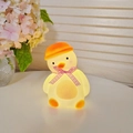 Cute yellow chicken night light with orange hat and pink checkered bow in warm glow - Tilted Head Duck - Pink