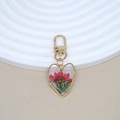 Detail of heart resin keychain with pink dried flower and gold metal edge on white stand - Red Flower
