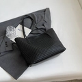 Minimalist black woven tote bag for office commuting placed on a grey blazer suit - Black