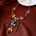 Detalle de un collar dorado vintage con piedras coloridas, perlas blancas y borlas elegantes - Dorado-Multicolor