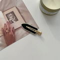 Close-up van de elegante zwart-gouden haarklem op een vintage boek en geurkaars - Zwart