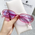 Close-up of translucent purple cat eye sunglasses held by hand over a white case - Pink Frame / Purple Lenses