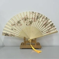 Classic folding hand fan with cherry blossom pattern and yellow tassel on wood stand - Floral Morning Moonlight