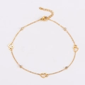 Makro-Detail von goldenem Hohlherz-Anhänger und rundem Zirkonia an minimalistischer Fußkette - Gold