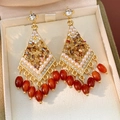 Vista detallada de pendientes de rombo vintage con perlas y borlas de cuentas rojas - Estilo de borla de rombo / Marrón dorado