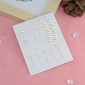 White pearl earring set with 14 pieces of various sizes displayed on pink fabric background - Pearl Sticker Set