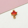 Detailed macro view of a gold plated geometric rhombus pendant with a red zircon stone - Orange Red