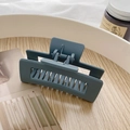 Matte blue-grey rectangle claw clip for thick hair shown on a wooden desk setting - Matte Blue Grey Hollow Hair Claw