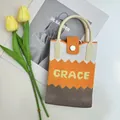 Detail of knitted tote bag featuring orange zigzag pattern and woven GRACE lettering - Color Block Orange-Grace
