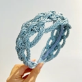 Detailed view of light blue braided faux leather headband with intricate weave texture - Blue