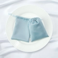 Pair of light blue satin drawstring pouches for jewelry storage on white plate - Blue
