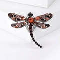 Detailed view of dragonfly brooch with deep red rhinestones and silver metal base - Purple