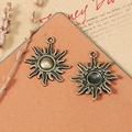 Vintage bronze sun charms for DIY jewelry making on orange textured mat with lavender decor - Bronze