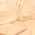 Gros plan d'une chaîne dorée avec pendentif feuille d'érable bleu clair sur cristal - Rose bonbon