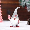 Close-up view of a handcrafted wooden Christmas gnome figurine holding a red gift box - Holding Gift Box Style / Grey Hat Rudolph
