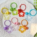 Set of eight colorful acrylic star keychains with matching bells on a white plate - Transparent Mixed Colors