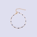 Detailed close-up of golden lip chain with black enamel beads and lobster clasp - Gold + Black