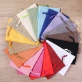 Linen drawstring jewelry pouches in various vibrant colors on a wooden background - Mixed