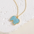 Close-up of sky blue elephant pendant with mosaic shell inlay on a gold cross chain - Blue