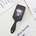 Detalle de un cepillo de pelo negro con diseño floral de calavera sobre un escritorio blanco - Calavera