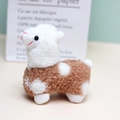 Primer plano de un pequeño peluche de alpaca con textura rizada y ojos adorables - 12cm / Camel