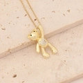 Close-up of golden bear necklace with zircon inlays on a beige textured stone base - Belly Pave Zircon Bear (10#)