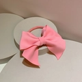 Macro detail of a large pink matte satin bow hair tie on a minimalist stone pedestal - Hair Tie / Pink