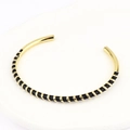 Detail of bohemian gold and black enamel stripe cuff bracelet on a white display base - Black