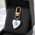 Macro shot of heart-shaped evil eye pendant with gold clasp on black velvet jewelry box - White Heart