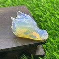 Macro shot of 4cm opal crystal dragon head figurine on a dark wooden stand - Synthetic Opal