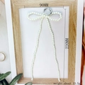 Macro detail of cream pearl bow pendant with dimensions 90mm by 220mm in a wooden frame - Long Leg Pearl Bow