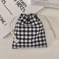 Close-up of a black and white gingham drawstring pouch on a minimalist desktop - Black Gingham Seersucker (Small)