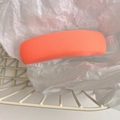 Close-up of a pink padded fabric hairband with soft texture in a white wire basket - Orange