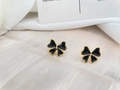 Detail of bow-shaped black enamel earrings with gold trim on ivory silk fabric - Black